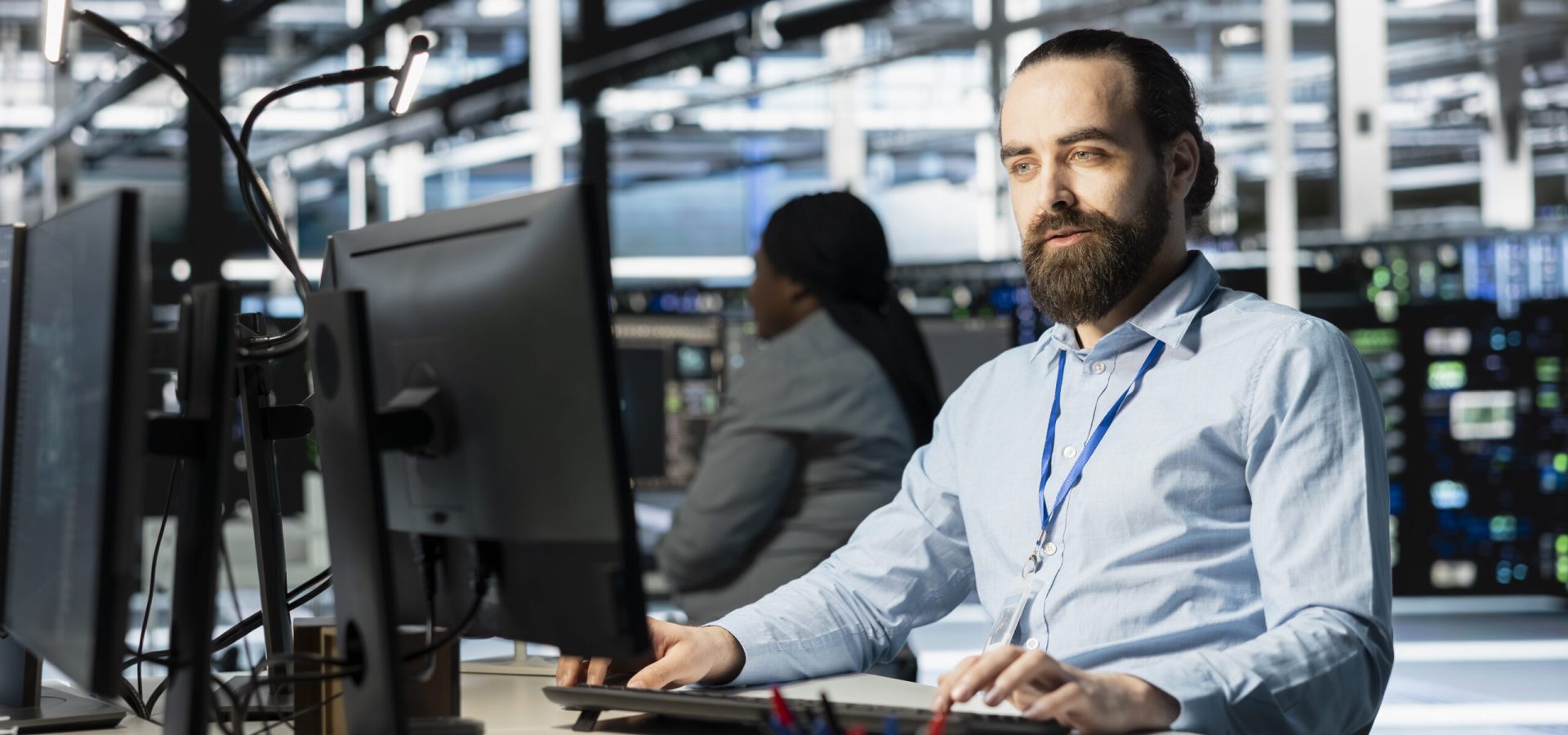 Data center programmer using PC to update servers tech, configuring gear using software tools. Server farm worker reviewing hardware analytics, ensuring reliable network operations